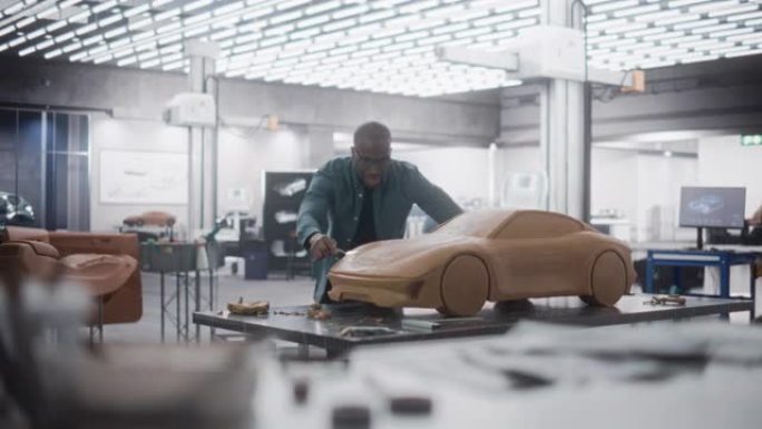 汽车建模师进入创意工作场所，从事由橡皮泥造型粘土制成的概念车。非洲设计师使用刮铲来平滑现代电动跑车的