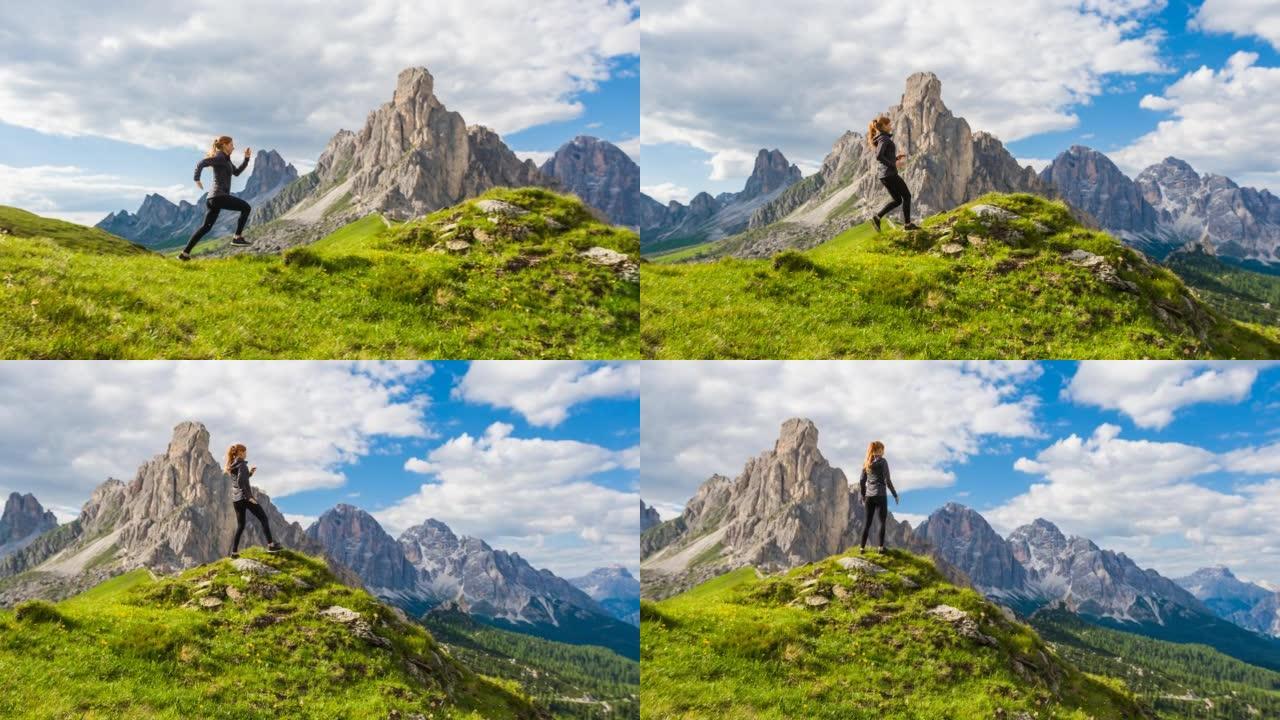 年轻的健康女人在多洛米蒂山脉的草地上奔跑，停在边缘，欣赏美景