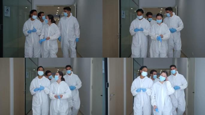 一群拉丁美洲前线工人在医院走廊上走时脱下手套