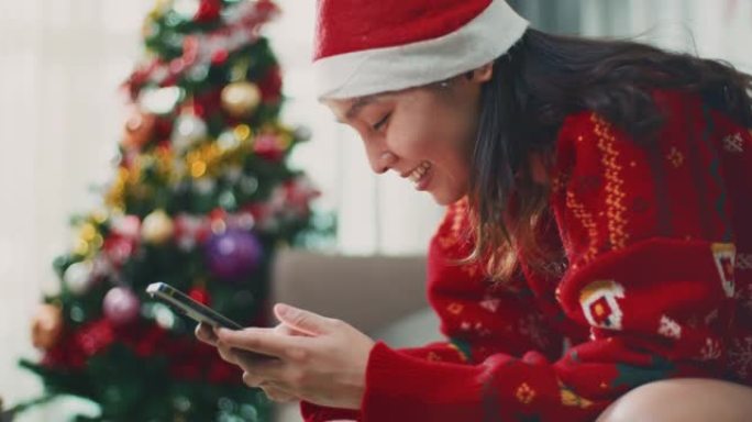 快乐的女人在圣诞节使用她的智能手机