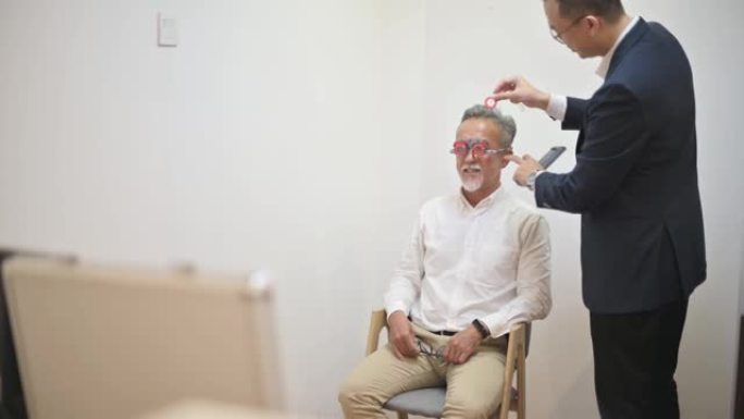 在眼科诊所检查视力的亚洲中国高级男子患者