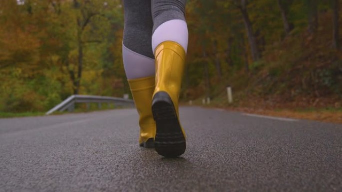 特写: 女性旅行者在沿着森林路线行走时穿着橡胶靴