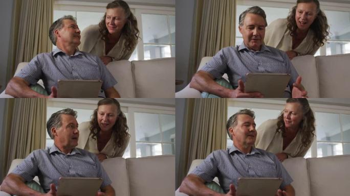 快乐的高级高加索夫妇在客厅使用平板电脑和聊天