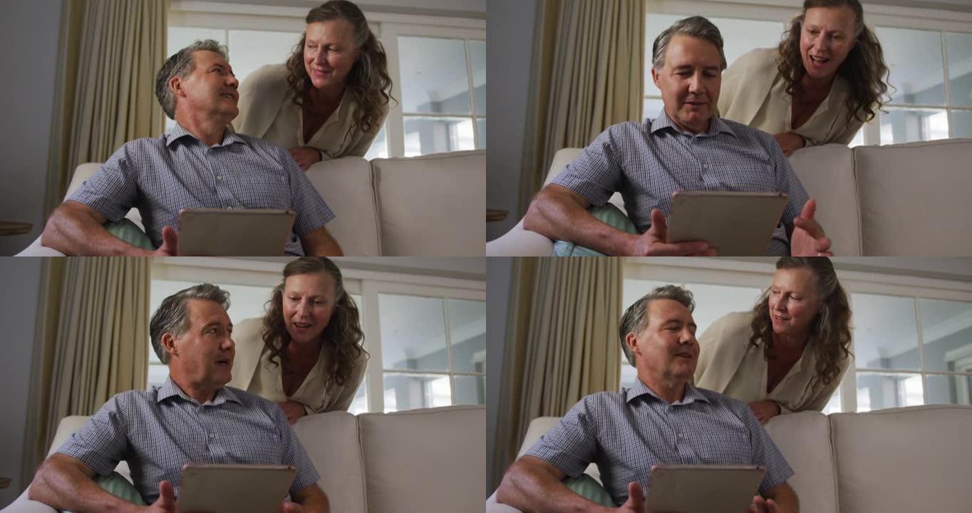 快乐的高级高加索夫妇在客厅使用平板电脑和聊天