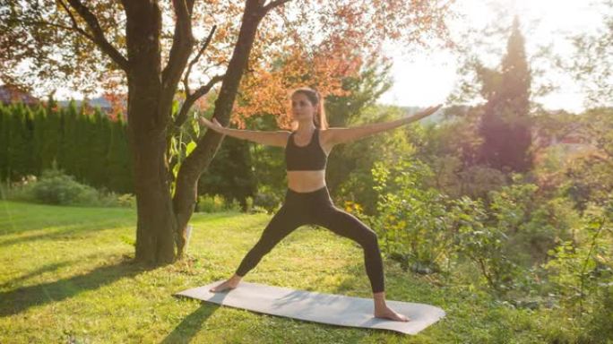 身体意识强的女人保持健康的生活方式，在后院外面摆出瑜伽姿势