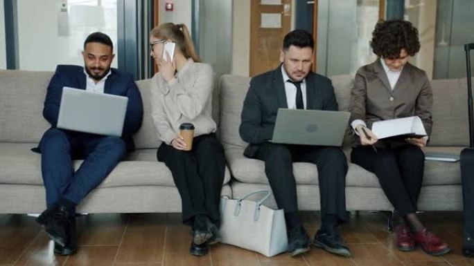 一群男女使用笔记本电脑在酒店大厅打电话聊天