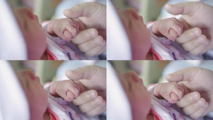 母亲在医院分娩后用手抚摸婴儿的小手