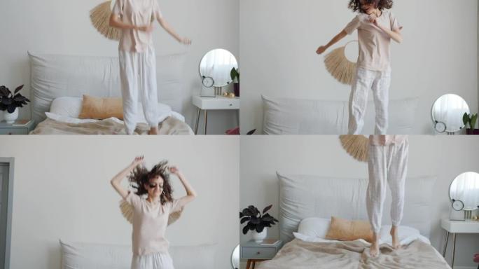 快乐的年轻女士穿着睡衣跳舞，在床上跳，在家里玩得开心