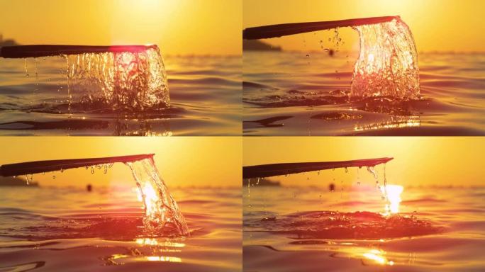 特写: 金色日出照亮的水滴从桨上滴下来