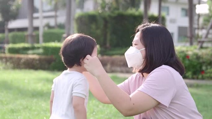 母亲为儿子戴上口罩，以保护母亲免受新型冠状病毒肺炎病毒的传播，并在早晨看到早晨的阳光。