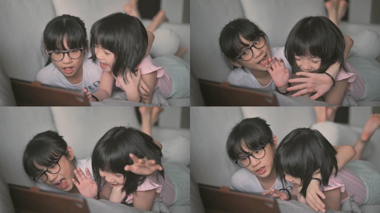 亚洲华裔年轻女孩在客厅用数字平板电脑在线与父亲交谈，躺在沙发上快乐地躺着