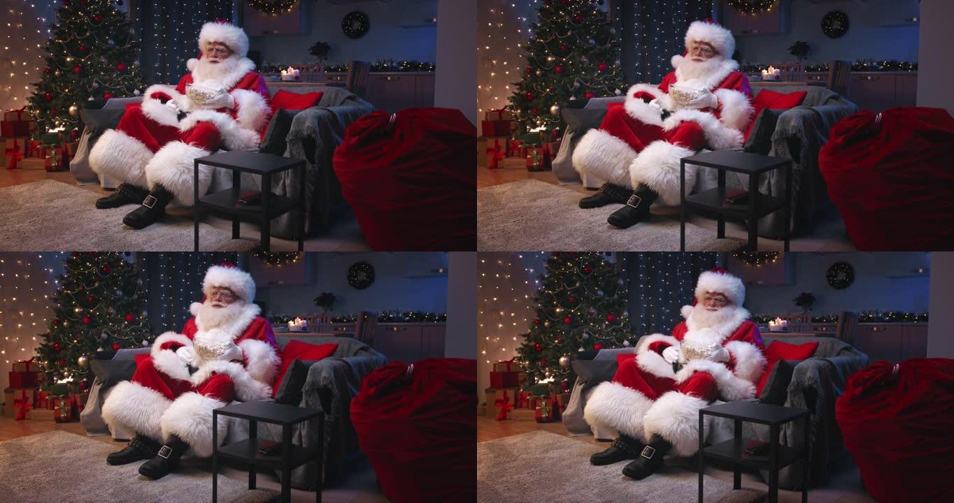 圣诞老人坐在装饰精美的客厅里过圣诞节，坐在灰色的沙发上看电视，吃着爆米花。圣诞老人对电视上播放的情节