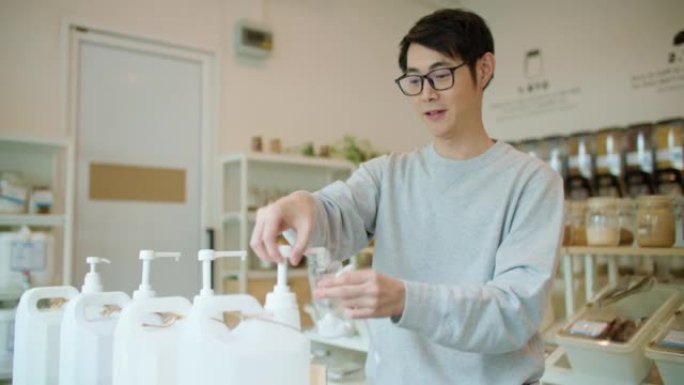 男子从塑料免费商店的容器分配器重新填充天然生物产品。