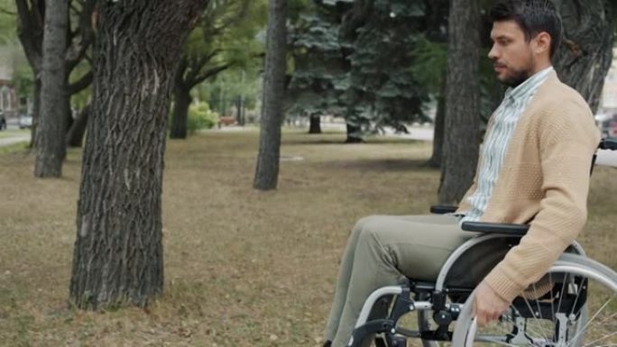 坐轮椅的严重残疾男子在城市独自一人在秋天用手移动轮子