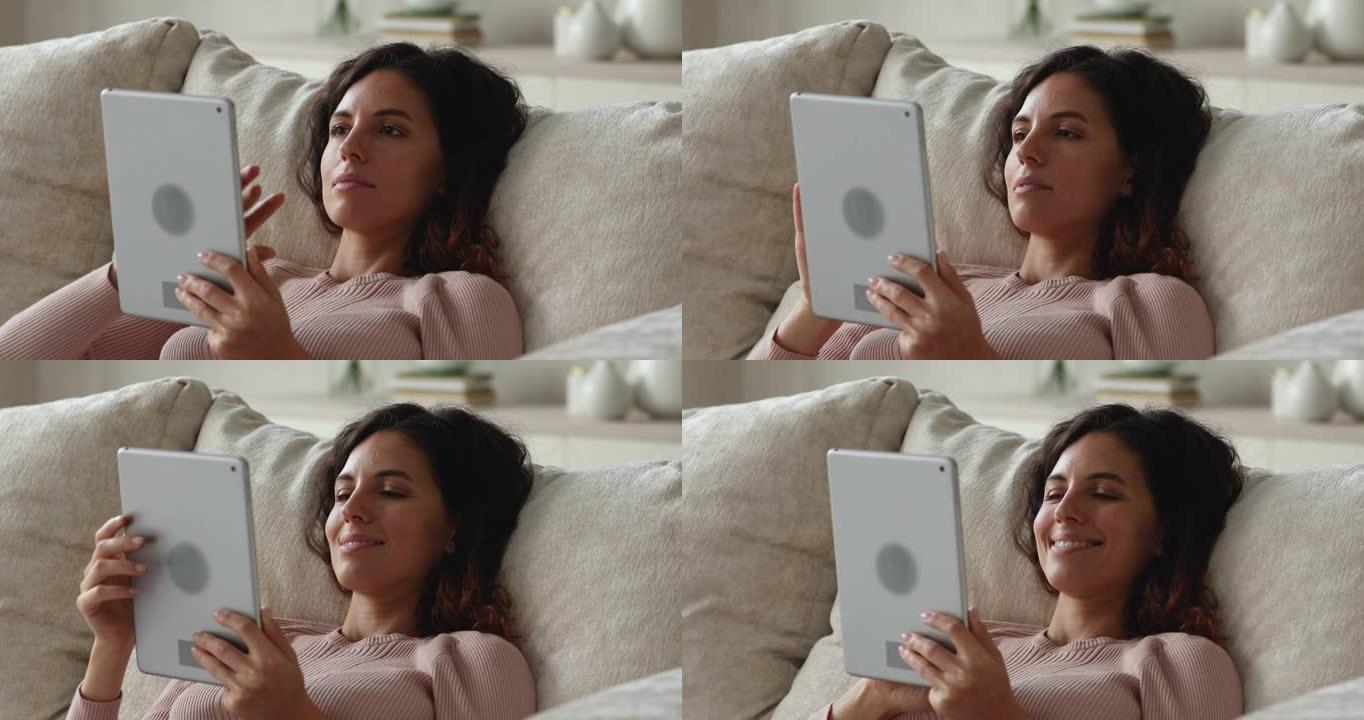 轻松微笑的千禧一代西班牙裔女性使用数字平板电脑。