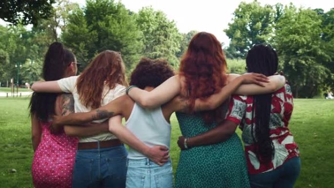 不同的女性朋友在公园里散步，互相拥抱，说说笑笑。一群享受夏日天气的多民族年轻女性