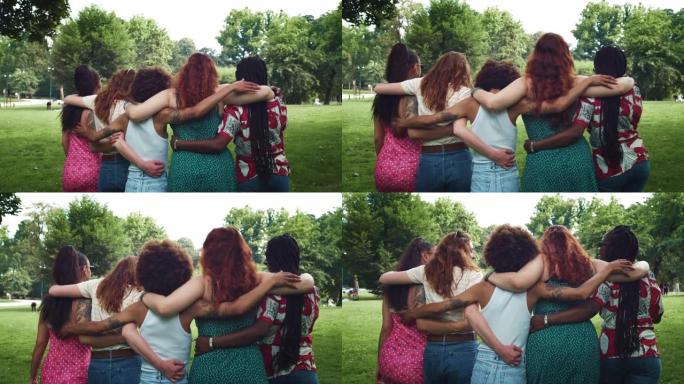 不同的女性朋友在公园里散步，互相拥抱，说说笑笑。一群享受夏日天气的多民族年轻女性