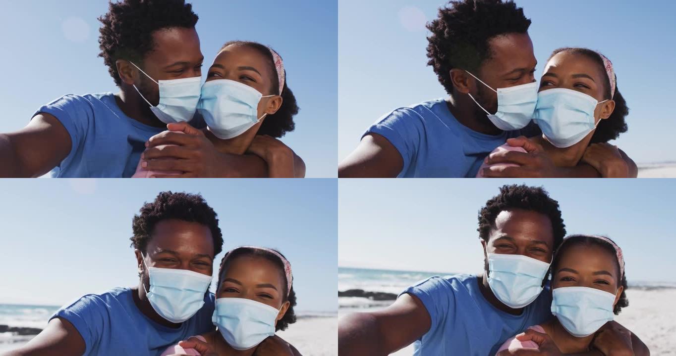 戴着口罩的非洲裔美国夫妇在海滩上看着相机的肖像