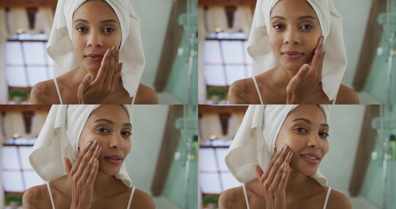 混合种族妇女的肖像头上戴着毛巾在脸上涂上奶油