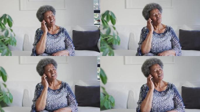 非裔美国高级妇女坐在沙发上并使用智能手机