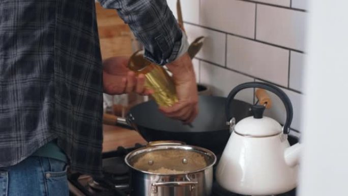 在厨房里做饭，晚餐和男人，在家里的炉子上放食物和油。人们在早餐或午餐中准备健康营养，健康和健康的餐点