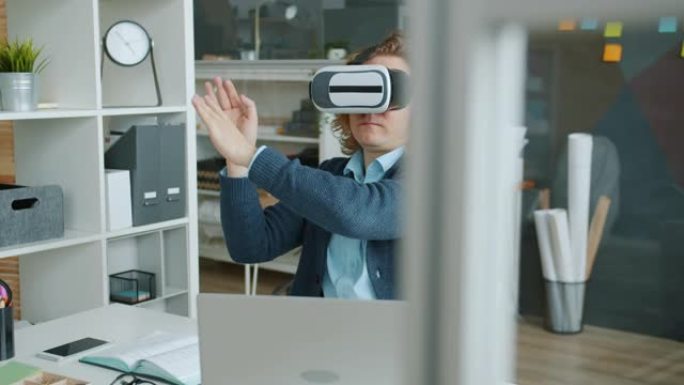 戴着虚拟现实眼镜的家伙在办公桌前移动手臂的慢动作