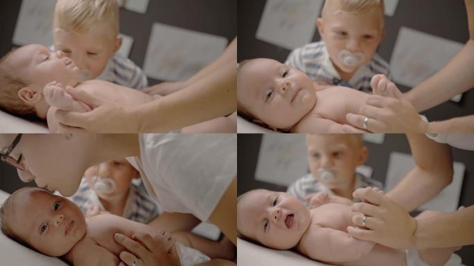 SLO MO的母亲拥抱一个婴儿男孩，而他的弟弟看着他