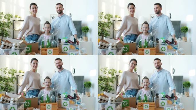 幸福的年轻家庭的肖像站在家里，带着一箱垃圾进行回收