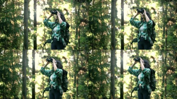 年轻女子在森林里用双筒望远镜