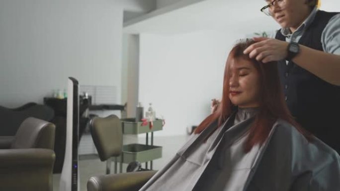 慢动作美发沙龙亚洲中国女性发型师吹梳湿长发为她的顾客在发廊