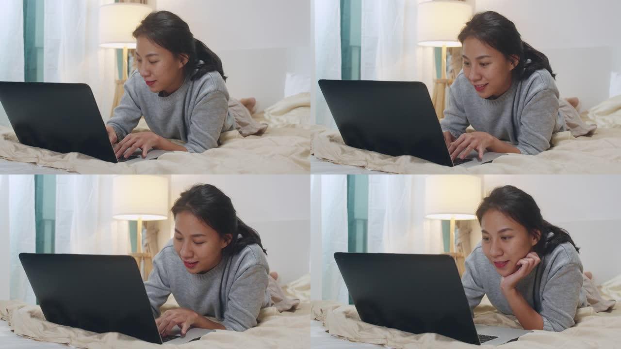 自由亚洲女性休闲服的肖像在卧室的卧室里使用笔记本电脑在家里晚上。