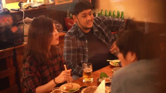 亚洲夫妇和朋友在日本居酒屋餐厅酒吧吃喝啤酒