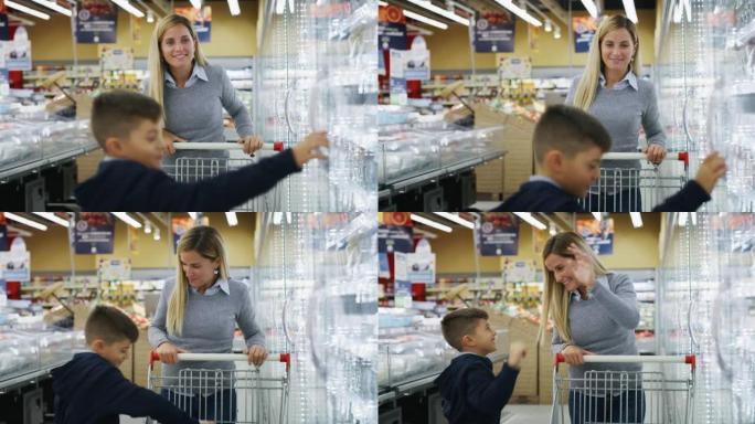 地地道道的快乐母亲带着篮子和儿子在超市一起买杂货时玩得很开心。