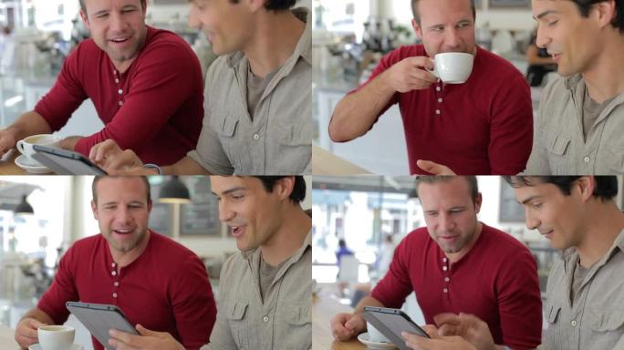 咖啡店里的两个男性朋友看着数字平板电脑