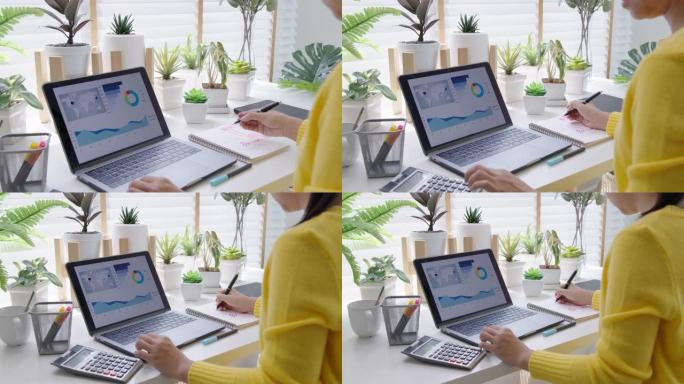 女商人在家工作销售报告的后视图。亚洲青年中小企业所有者企业家使用笔记本电脑和平板电脑在线分析。远程工