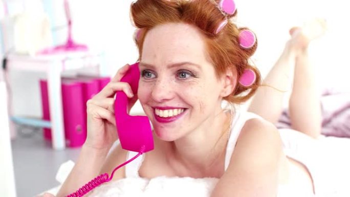 女孩在床上用粉红色电话聊天