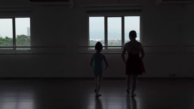 剪影亚洲中国少女芭蕾舞演员在工作室训练她的年轻女学生