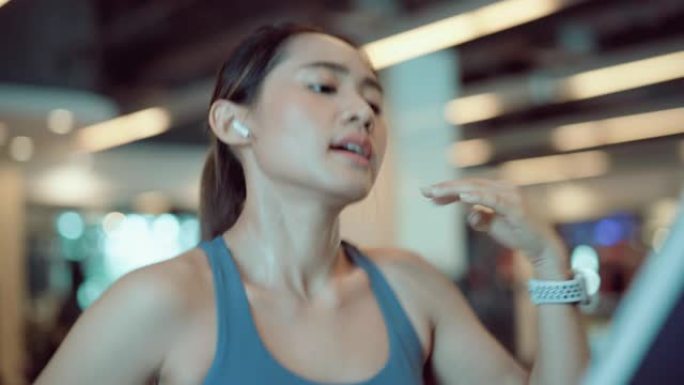 在健身房的跑步机上跑步的亚洲女性。