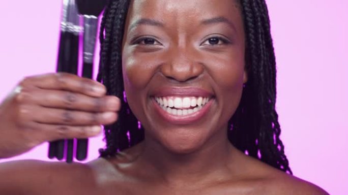 4k视频片段，一名妇女在粉红色背景下拿着一组化妆刷