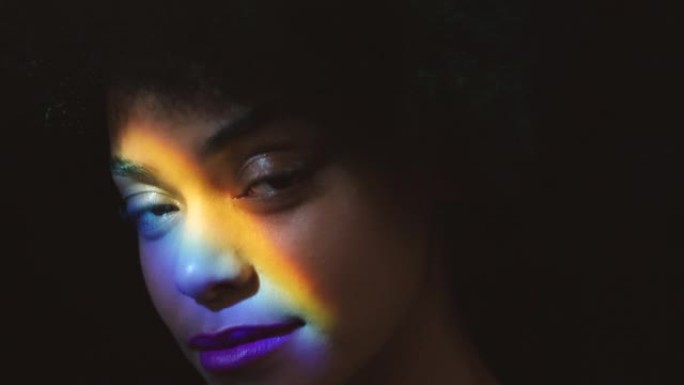 彩虹，棱镜光和一个黑人女人的脸，有创意的灯光反射。来自牙买加的年轻模特的肖像放松，在皮肤上的彩色艺术