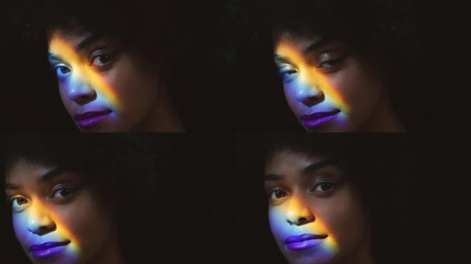 彩虹，棱镜光和一个黑人女人的脸，有创意的灯光反射。来自牙买加的年轻模特的肖像放松，在皮肤上的彩色艺术