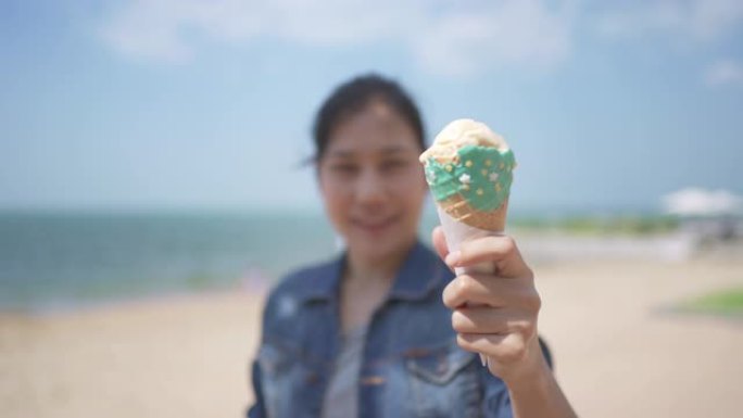 夏天在海滩上展示冰淇淋蛋卷的亚洲妇女
