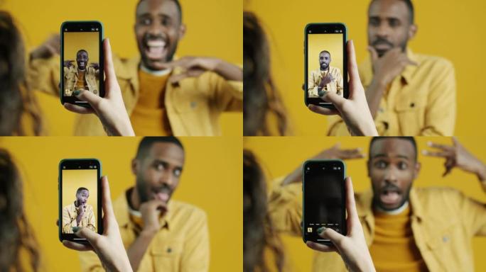顽皮的非洲裔美国人在触摸屏幕拍照时摆出智能手机相机的姿势