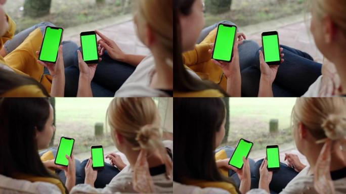 DS两名妇女在露台上使用带有色度键绿色屏幕的智能手机