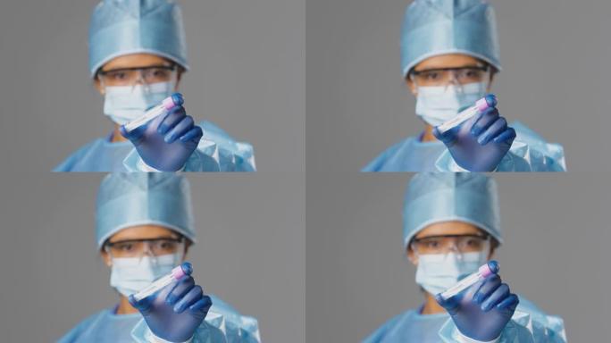 女实验室研究人员，穿着个人防护用品，戴着安全眼镜，拿着带有棉签的PCR试管