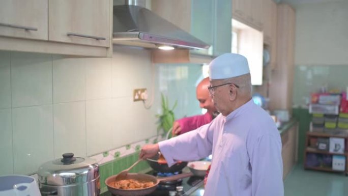 马来家庭祖父和父亲在厨房里并排烹饪传统食物咖喱，为哈里拉雅家庭团圆饭做准备