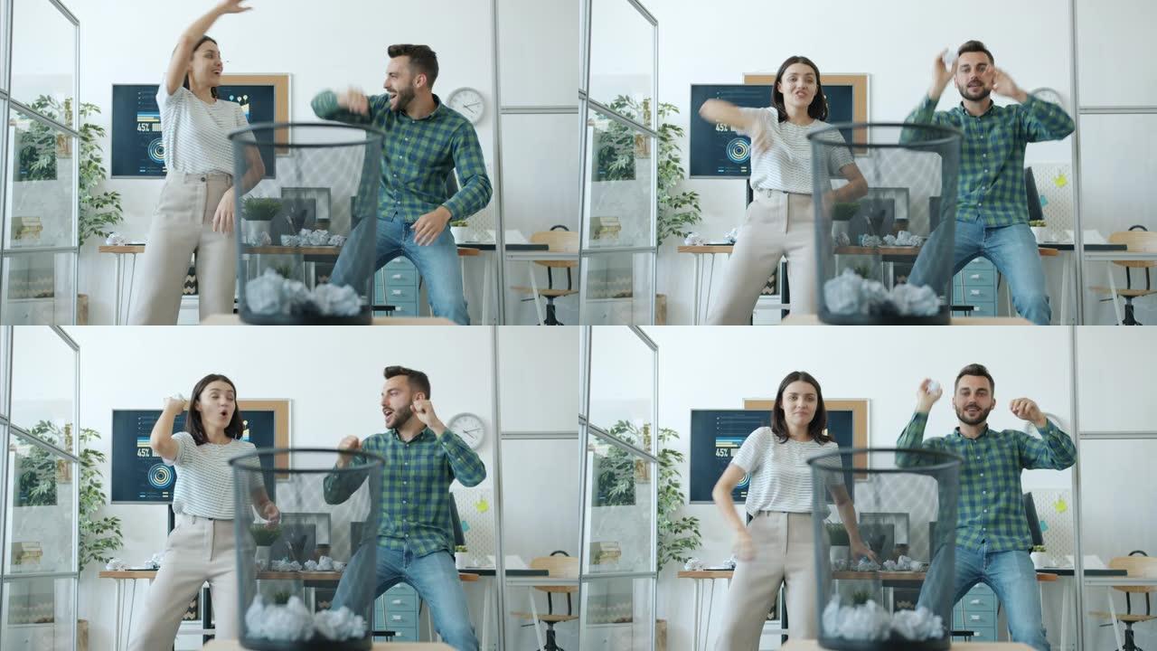快乐的男人和女人在办公室打篮球，在篮子里扔纸球，做击掌大笑