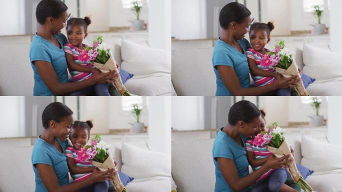 快乐的非洲裔美国母女坐在沙发上闻着鲜花