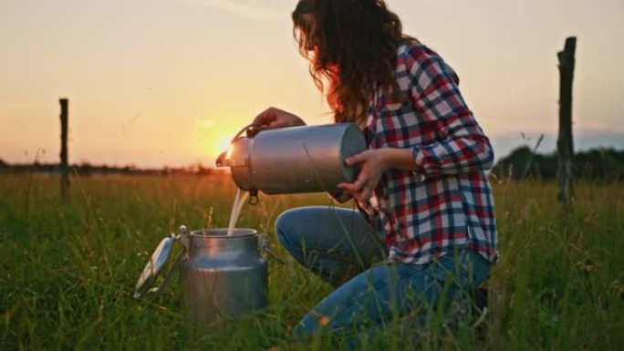 SLO MO年轻女子在日落时在牧场上从一个罐子倒牛奶到另一个罐子