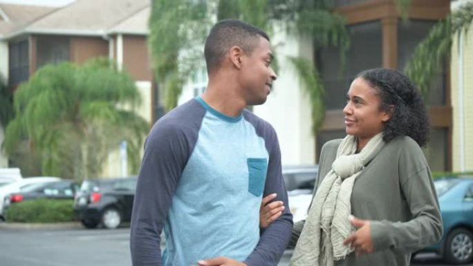 年轻的黑人夫妇在公寓楼停车场，交谈